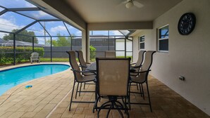 A covered patio with a pool, outdoor seating, and a ceiling fan.