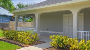 A residential house with a covered porch, a stone wall, and a well-maintained lawn.