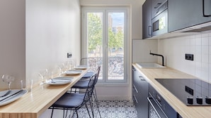 Eine moderne Küche mit Essbereich, ausgestattet mit einem großen Fenster, einem schwarzen Backofen und einer Holz Arbeitsplatte.