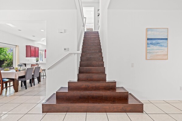A staircase leading to a second floor, with a dining area and a painting on the wall. - Bright Airy 5B Home Workspace Outdoor Lounge (Moreno Valley)