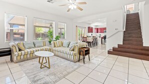 A spacious living room with two sofas, a coffee table, and a staircase leading to a kitchen area. - Bright Airy 5B Home Workspace Outdoor Lounge (Moreno Valley)