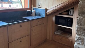 Una cocina de madera con estufa integrada, armarios de madera y una pared de piedra.