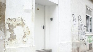 Eine weiße Tür mit der Beschriftung '3A', ein kleiner Briefkasten und ein Fenster zur Rechten. An der Wand ist Graffiti zu sehen.