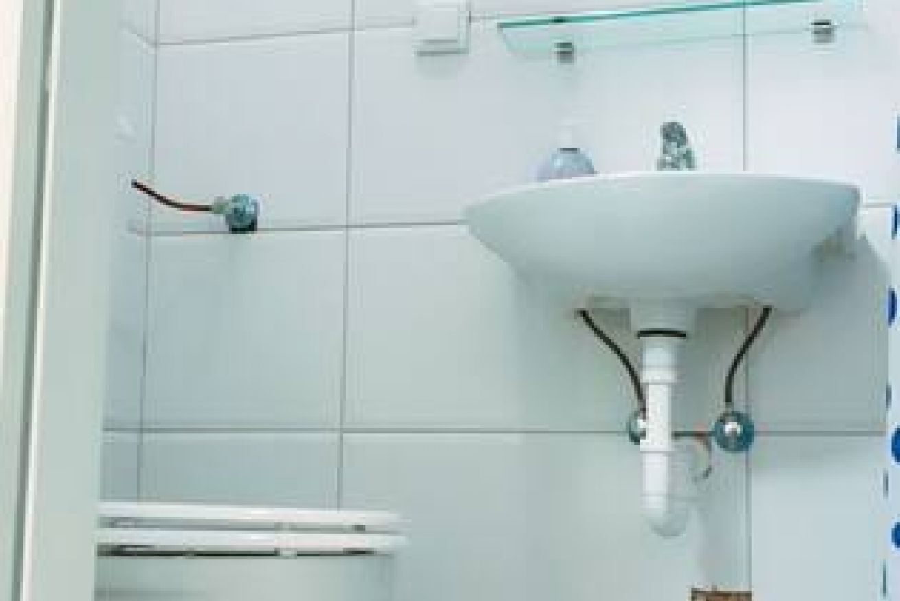 A bathroom with a white sink, a glass shelf, and a towel rack.