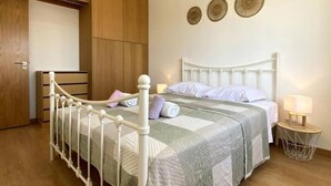 A bedroom with a bed, wooden wardrobe, and a bedside table with a lamp. - Casa do Rio, Algarve, charming renovated traditional house, ideal location (Parchal)