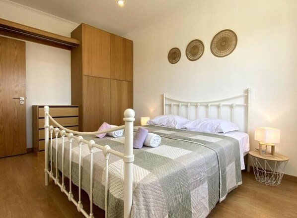 Un dormitorio con cama, armario de madera y mesita de noche con lámpara.