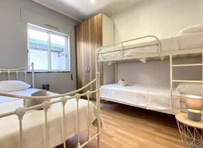 Una habitación con literas, una ventana con vistas y una mesita de noche con lámpara.