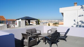 A rooftop terrace with wicker furniture, a small table, and a solar panel. - Casa do Rio, Algarve, charming renovated traditional house, ideal location (Parchal)