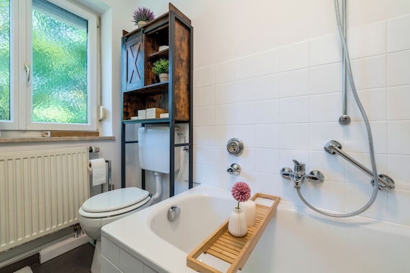 A modern bathroom with a toilet, bathtub, and shower.