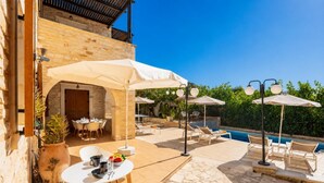 An outdoor patio with a pool, stone flooring, and outdoor seating.