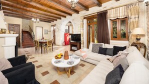 A cozy living room with a fireplace, a dining area, and a kitchen in the background.