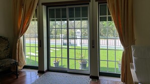 A room with a large sliding glass door leading to a balcony with a view of a park and a building.