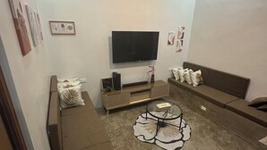 Una sala de estar con una televisión de pantalla plana grande, un sofá y una mesa de centro.