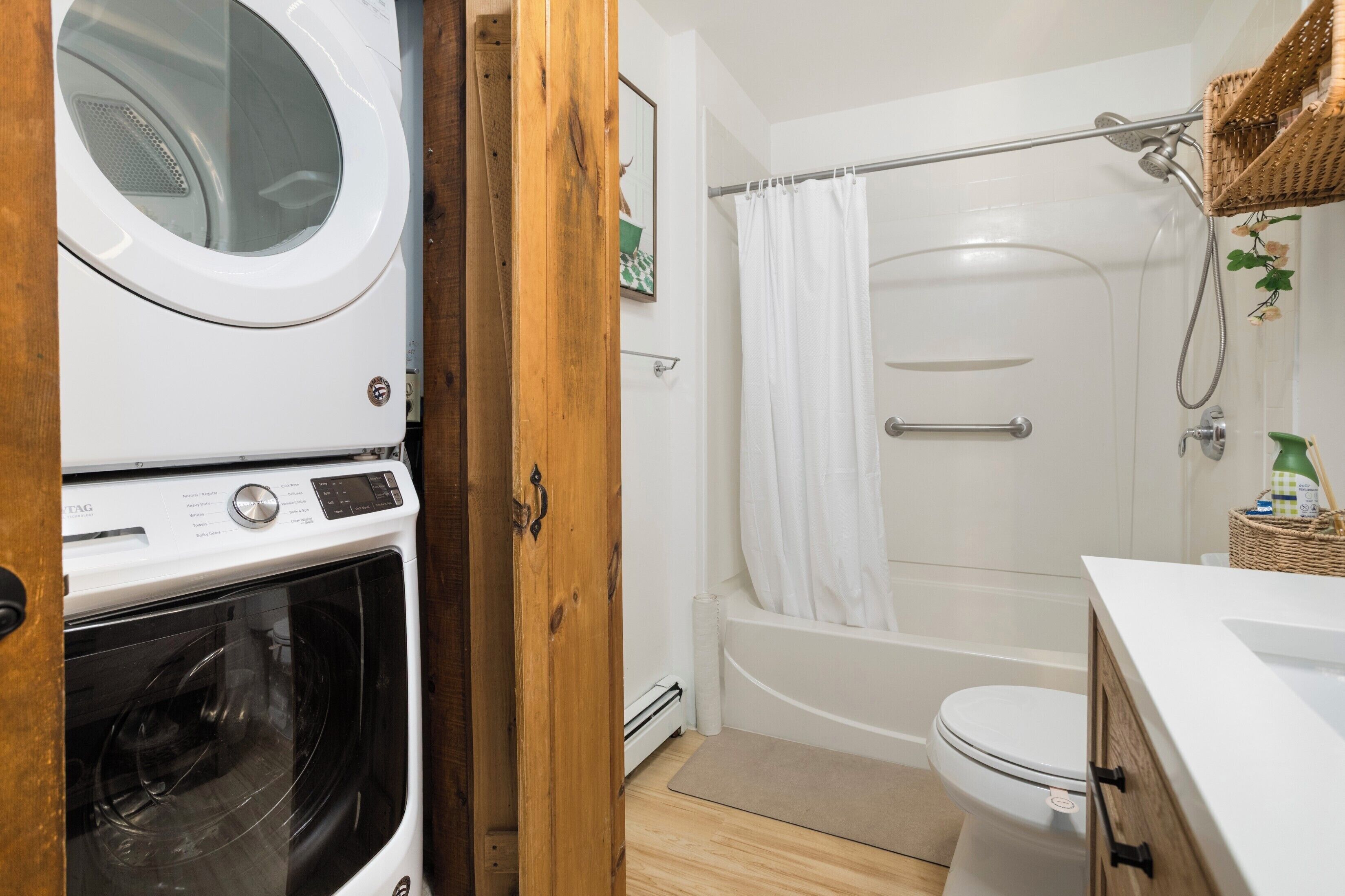 Une petite salle de bain équipée d’un lave-linge, d’une baignoire et de toilettes.