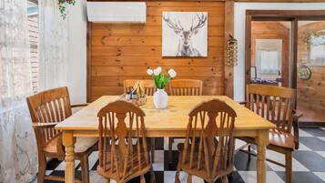 A wooden-paneled room with a checkered floor, a wooden table with chairs, a vase with flowers, and a deer painting on the wall.