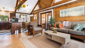 Interior acogedor de una cabaña con vigas de madera, un comedor, un sofá con cojines y una mesa de centro.