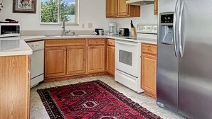 Une cuisine avec des meubles de rangement en bois, un réfrigérateur en acier inoxydable, un four à micro-ondes et une cuisinière.