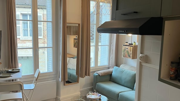 Una cocina moderna con estufa integrada, una zona de comedor con mesa de vidrio y un sofá.