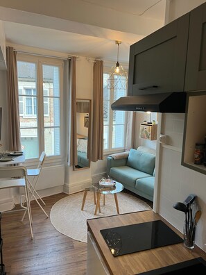 A modern kitchen with a built-in stove, a dining area with a glass table, and a sofa.