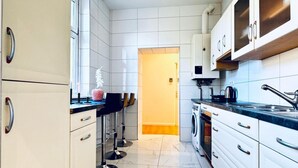 Una cocina moderna con armarios blancos, lavadora y cafetera.