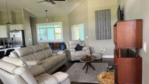 A spacious living room with a large beige sectional sofa, a smaller armchair, and a coffee table. There is a wooden TV stand and a decorative wall piece. - Sunny Daze lake time is always a great time! (Lake Placid)