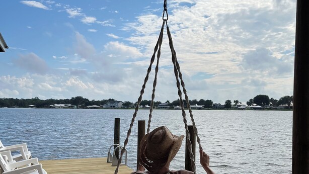 A wooden deck with a hammock chair and a white rocking chair. - Sunny Daze lake time is always a great time! (Lake Placid)