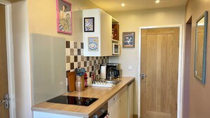A compact kitchen with a built-in oven, a coffee maker, and a dish rack.