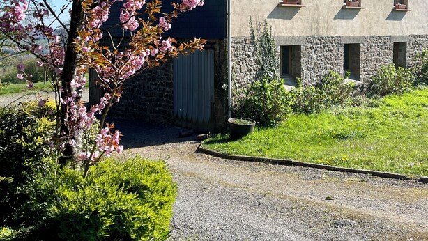A two-story house with a stone foundation and a tiled roof.