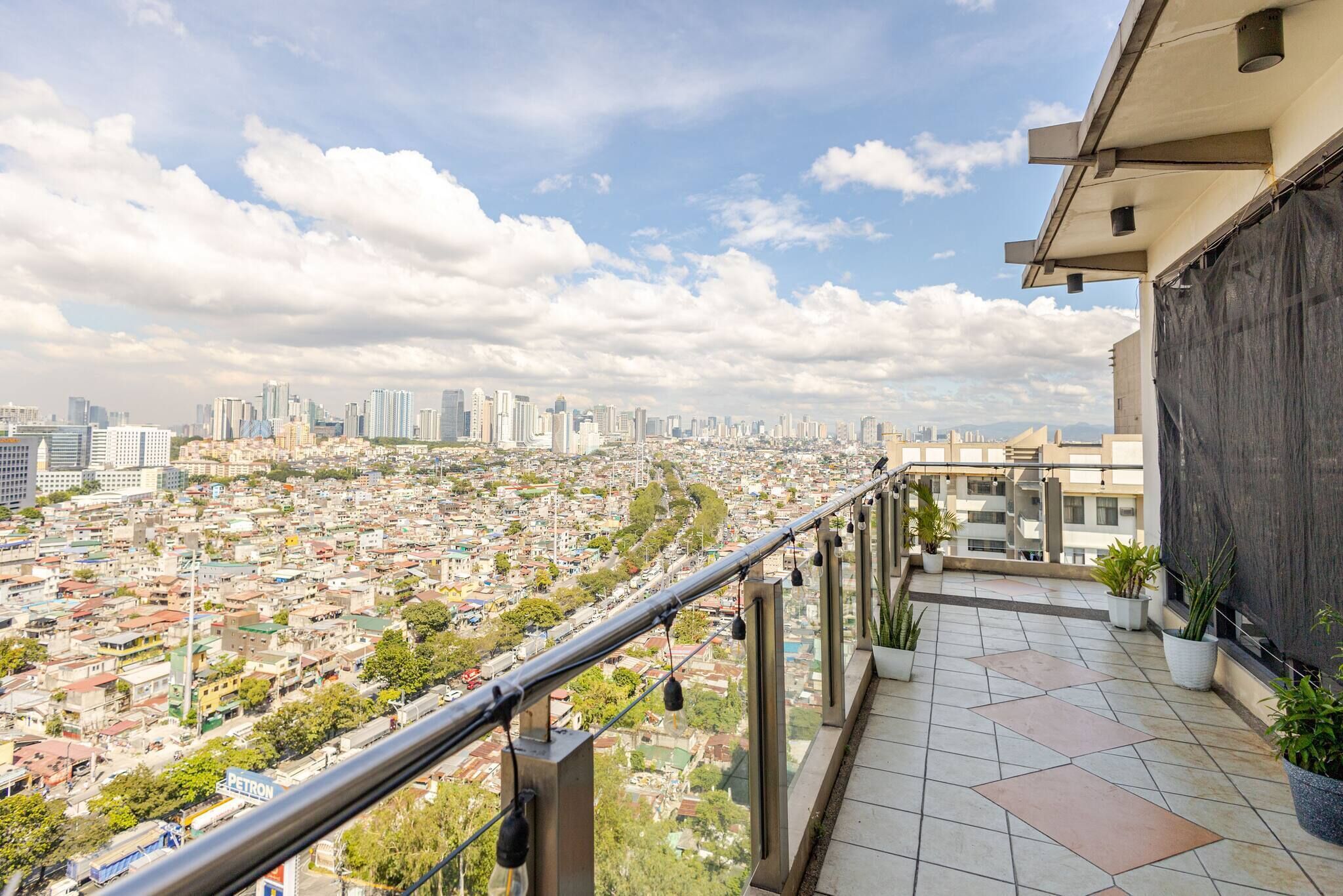 A balcony with a city view, potted plants, and a metal railing.