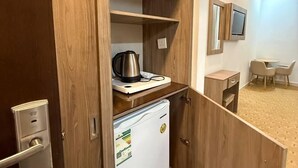 A compact kitchenette with a coffee maker, a small refrigerator, and a wooden cabinet.