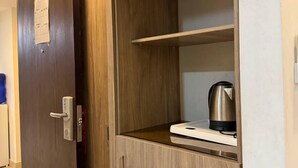 A wooden wardrobe with a built-in shelf and a kettle on top.