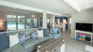 A modern living room with a sofa, armchairs, a coffee table, and a TV on a stand. - ☀️Private Pool | Pet Friendly | Curlew Beach Cottage☀️ (Fort Myers Beach)