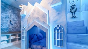 Ein Kinderzimmer mit einem Bett, Einbauschränken und einer Wandmalerei einer verschneiten Landschaft.