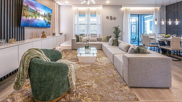 Ein modernes Wohnzimmer mit Flachbildfernseher, einer Couch, einem Couchtisch und einem Essbereich mit Tisch für zwei Personen.