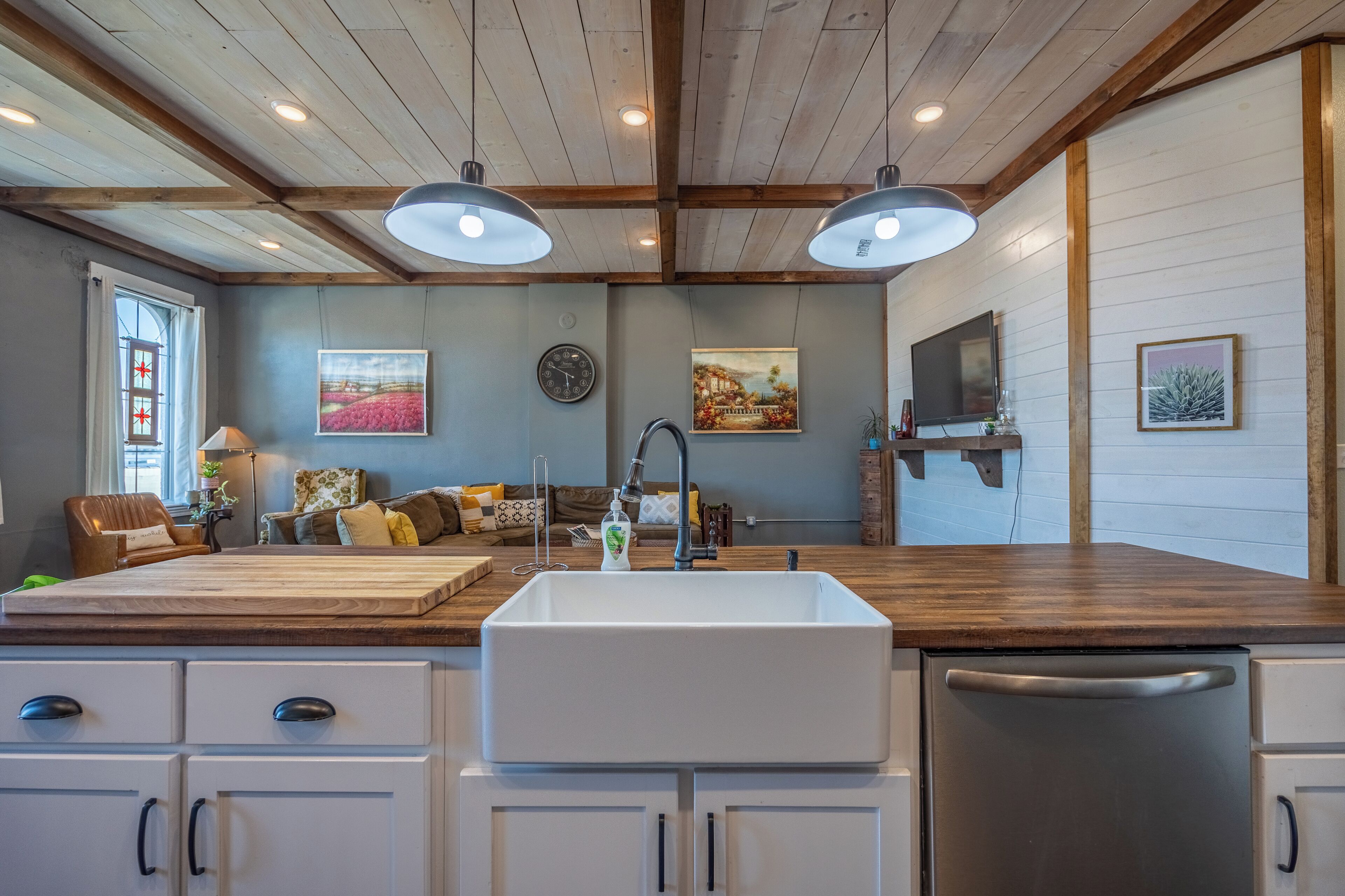 A kitchen with a large island, white cabinets, and a wooden ceiling.