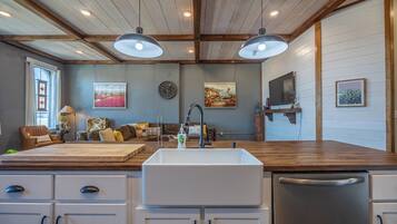 A kitchen with a large island, white cabinets, and a wooden ceiling.