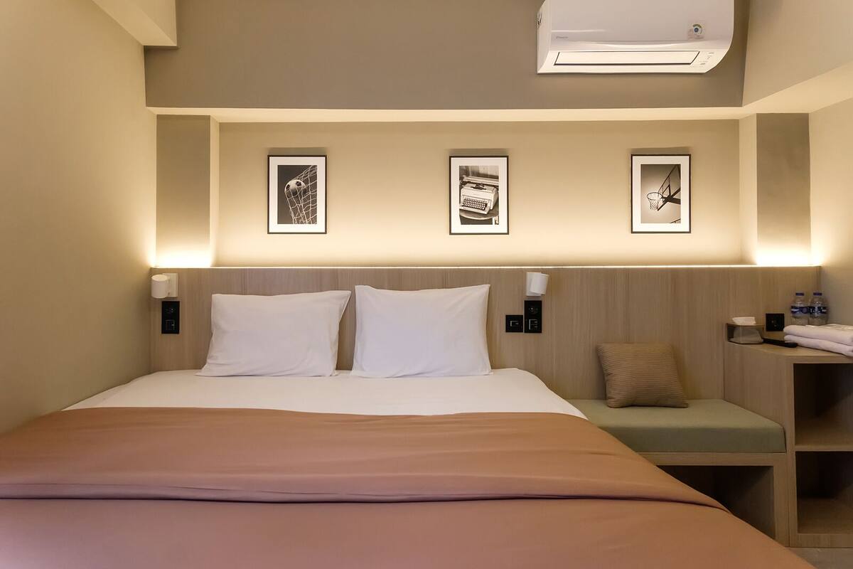 A hotel room with a bed, bedside tables, and wall-mounted artwork.