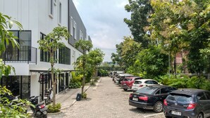 Una calle bordeada de coches aparcados y una hilera de edificios modernos con balcones.