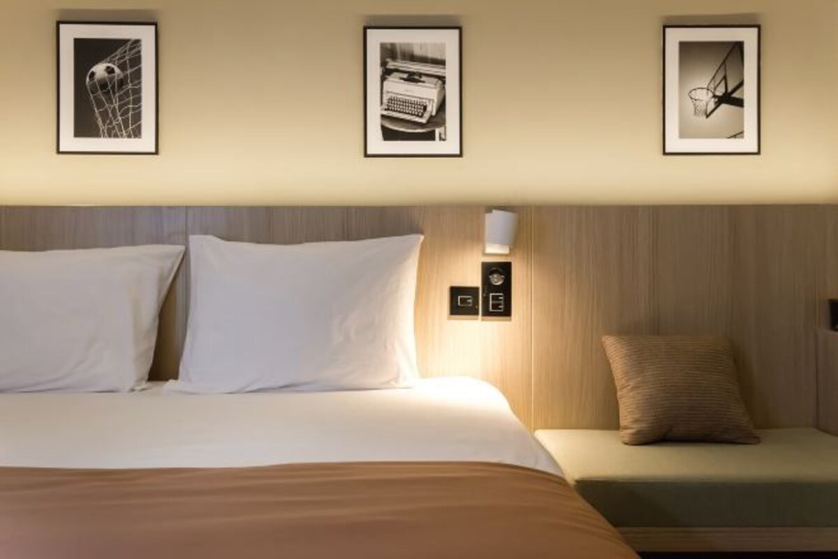 Et hotelværelse med en seng, et natbord og tre billeder hængende på væggen.