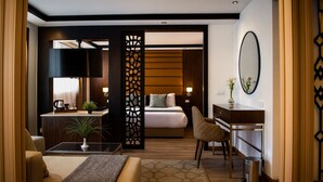 A modern hotel room with a bed, desk, chair, and a decorative partition. - Nile Cruise Suites Only every Friday from Aswan 3 nights & every Monday from Luxor 4 nights (Aswan)