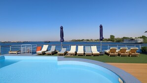 A poolside area with lounge chairs and umbrellas, overlooking a body of water. - Nile Cruise Suites Only every Friday from Aswan 3 nights & every Monday from Luxor 4 nights (Aswan)