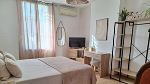 A bedroom with a bed, a desk, a chair, a TV, and a bookshelf. - Chez Christophe Pauillac  (Pauillac)