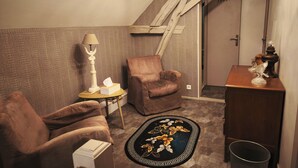 Una habitación acogedora con un sillón de cuero marrón, una mesita redonda con lámpara, un tapete decorativo y un armario de madera.