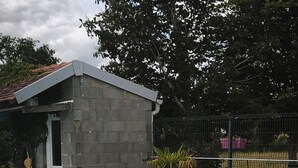 Una piscina con una pequeña estructura contigua, rodeada por una valla y vegetación.