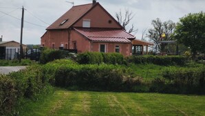 Una casa de un solo piso con techo rojo, rodeada de follaje y un cielo despejado.