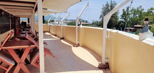 Un espace extérieur abrité, doté d’un long banc et d’un sol carrelé.
