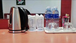 A hotel room with a kettle, two glass bags, water bottles, and a tray with glasses and a cup. - Neptuna Kata Beach Phuket (Karon)