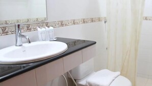 A bathroom with a white sink, a mirror, a toilet, and a shower curtain. - Neptuna Kata Beach Phuket (Karon)