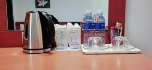 A hotel room with a kettle, two glass bags, water bottles, and a tray with glasses and a cup. - Neptuna Kata Beach Phuket (Karon)