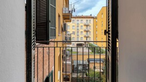 A view through a metal gate of a yellow building with multiple balconies and a brick wall. - BluesHouse Carracci Suites (Bologna)